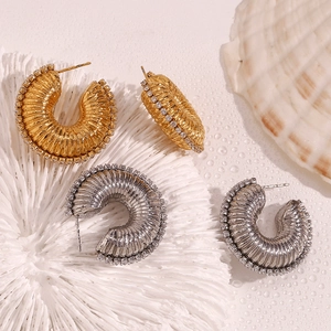 Detailed macro view of gold and silver plated textured hoop earrings with zircon border