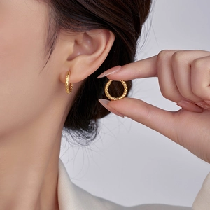 Detail shot of gold titanium steel hoop earrings with an intricate mesh woven texture