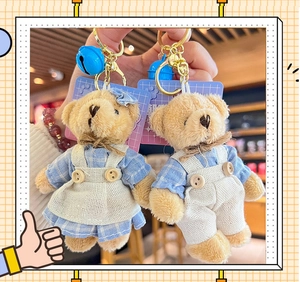 Detail of plush bear keychains featuring blue plaid outfits and bright blue bells