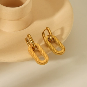 Detailed view of gold stainless steel huggie earrings with textured oval pendants