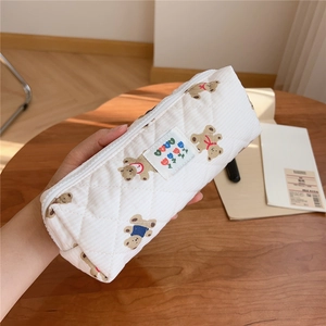 Close-up of quilted cream pencil case featuring cute brown bear and floral patterns
