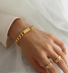 Detailed close-up of 18K gold plated curb chain bracelet and woven rings on hand