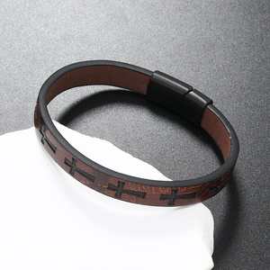 Macro detail of brown leather bracelet featuring black cross patterns and magnetic metal clasp