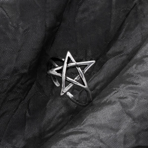 Detail of silver vintage pentagram ring with punk textured finish on dark fabric