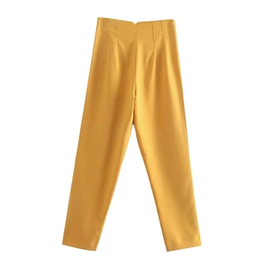 Detailed view of high-waisted bright yellow trousers with smooth fabric texture