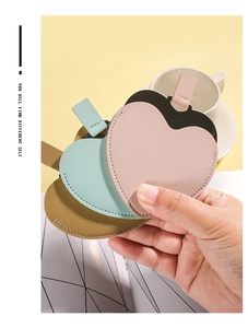 Close-up of portable heart-shaped PU leather mirrors in pink, green and yellow colors
