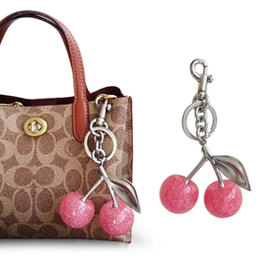 Detailed view of pink glitter cherry pendant with silver metal leaf and lobster clasp