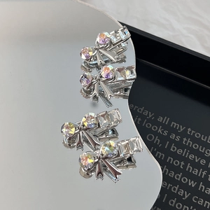 Detailed macro view of four silver alloy bow hair clips with sparkling colorful rhinestones