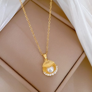 Détail du pendentif coquillage avec perle et cristaux sur chaîne dorée en titane