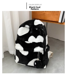Detail view of plush black and white polka dot backpack with a soot sprite charm