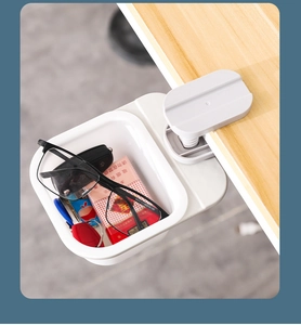 Detail of white plastic rotating desk-side storage box clamped on a wooden table edge