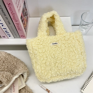 Detail of the soft yellow faux fur tote bag with a white brand label in a cozy setting