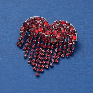 Luxurious red rhinestone heart brooch with sparkling tassel chains on a blue background
