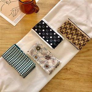 Dettaglio di vari foulard in seta con motivi floreali e geometrici su tavolo in legno