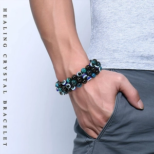Macro detail of men's triple-layer woven healing crystal bracelet with evil eye beads