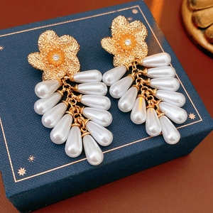 Détail de boucles d'oreilles fleur avec perles et cristaux sur une boîte bleue