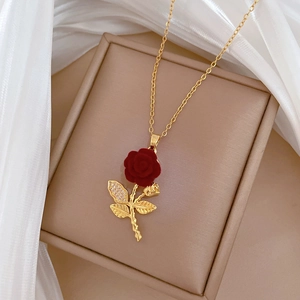 Detailed close-up of a golden necklace with a velvet red rose pendant and crystal leaves