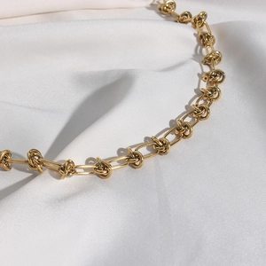 Dettaglio macro della collana a catena Figaro dorata su sfondo di seta bianca