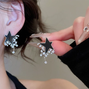 Close-up of a black star earring with zircon tassels worn on a model's earlobe