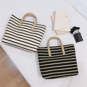 Two retro striped canvas tote bags with leather handles shown in a lifestyle setting