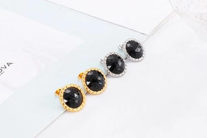 Close-up of circular stainless steel earrings with multifaceted black crystal stones