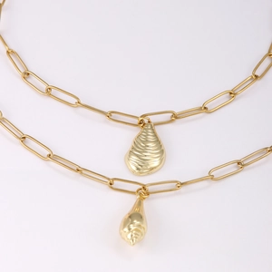 Gold layered necklace with paperclip chain and shell pendants on a white background