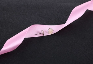 Macro view of round iridescent crystal stud earrings with silver base on silk ribbon