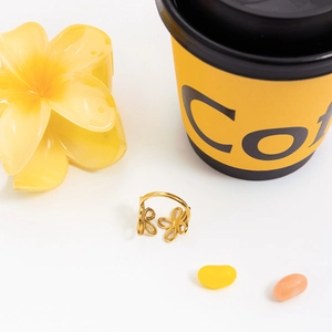 Detailed view of a gold flower ring with cutout petals on a minimalist white backdrop