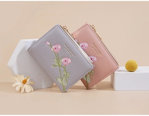 Detail of short leather wallets with floral embroidery and gold zipper closure