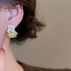 Detail shot of white flocked bear stud earring with gold hollow fan accessory on model