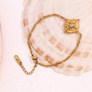 Close-up of 18K gold-plated star pendant with hammered texture and lobster clasp on a shell