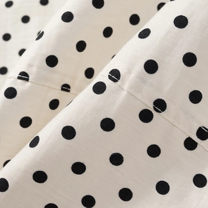Close-up of white fabric with black polka dots showing detailed texture and stitching