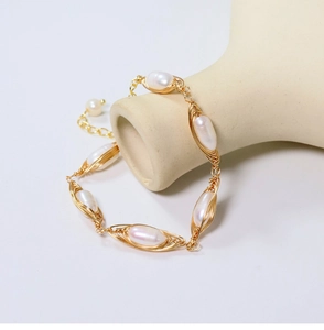Detailed view of natural rice pearls with gold wire wrapping on a white ceramic vase