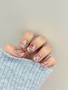 Detailansicht transparenter Fingernägel mit bunten Trockenblumen und feinen Glitzerakzenten