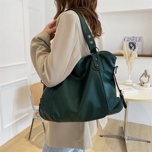 Minimalist large dark green tote bag in soft leather being worn by a stylish model