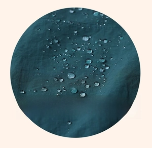 Detail view of waterproof and oil-proof dark green fabric with clear water droplets