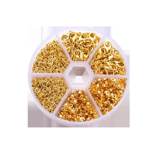 Close-up of golden lobster clasps, jump rings and crimp beads in a 6-grid storage box