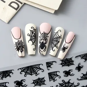Close-up of Halloween nail stickers with black spider webs and 3D metal spider charm