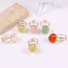 Detail of six handmade gold wire-wrapped rings with irregular natural raw gemstones