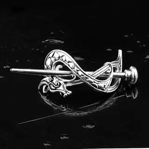 Detailed close-up of a silver Viking dragon hair slide with intricate Celtic metalwork