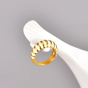 Close-up of gold croissant ring with beige enamel ribbing on a white ceramic plate