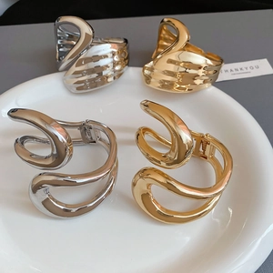 Detailed view of irregular geometric hollow metal bangles in polished gold and silver finish