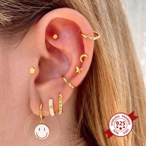 Detail of 925 sterling silver gold earrings with white enamel smile and star charms