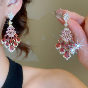 Macro detail of luxurious chandelier earrings with pink and burgundy pear-cut gemstones