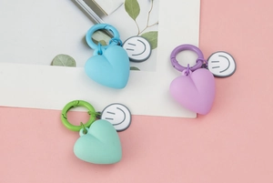 Close-up of heart-shaped keychains with smiley face tags in blue, purple, and green colors
