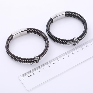 Dettaglio di bracciali in pelle intrecciata con croce e misura su un righello