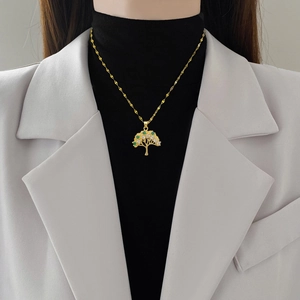 Elegant gold tree of life necklace with green and white crystals on a fashion model