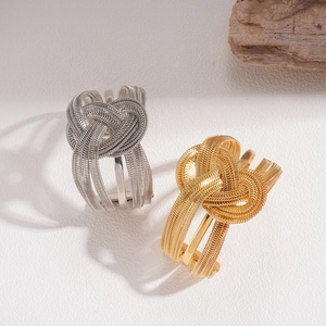 Detailed view of woven metal knot rings in gold and silver finish with elegant texture