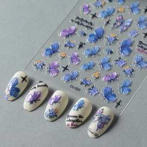 Macro shot of 3D embossed blue and purple butterfly nail art stickers on a beige tip