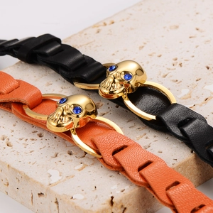 Skull braided leather bracelet with gold metal skull and blue gemstone eyes on rock
